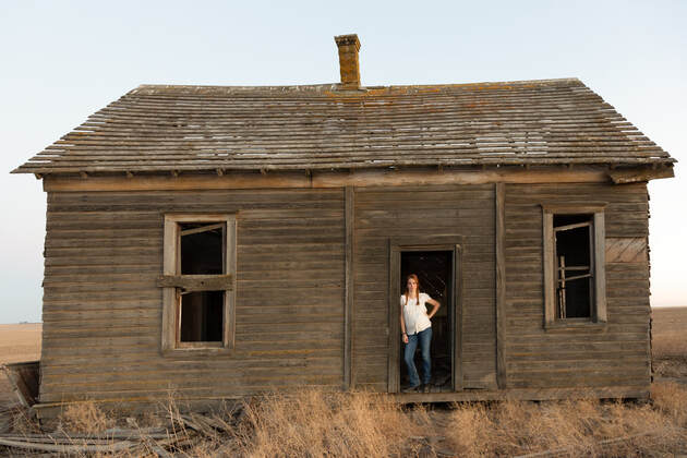 Farm girl in the doorway of an abandoned farmhouse